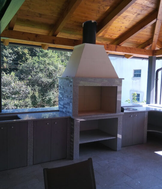 Odprti vrtni kamin na terasi s kobinacijo kamnitih pultov in omarami