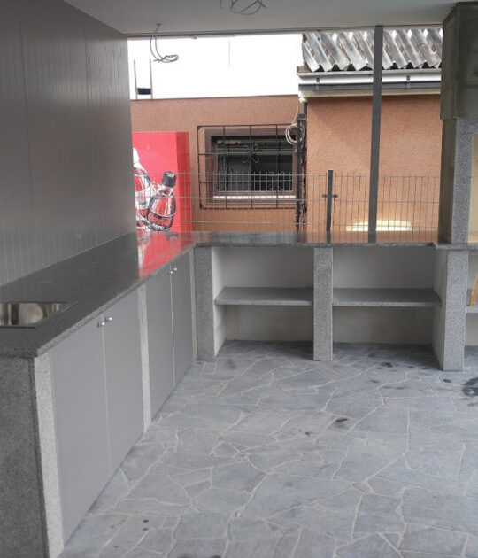 Vrtni kamin na terasi s podaljškom delovnih pultov v kamnu in omarami